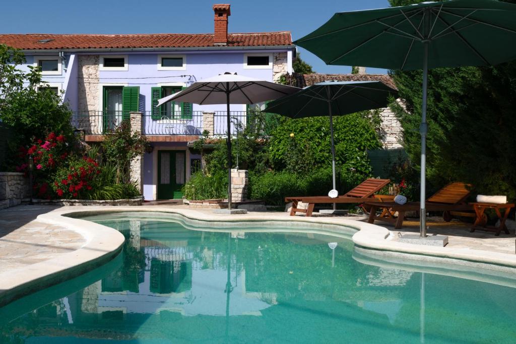 a swimming pool with two umbrellas and two chairs at Holiday Home Ladonja in Manjadvorci