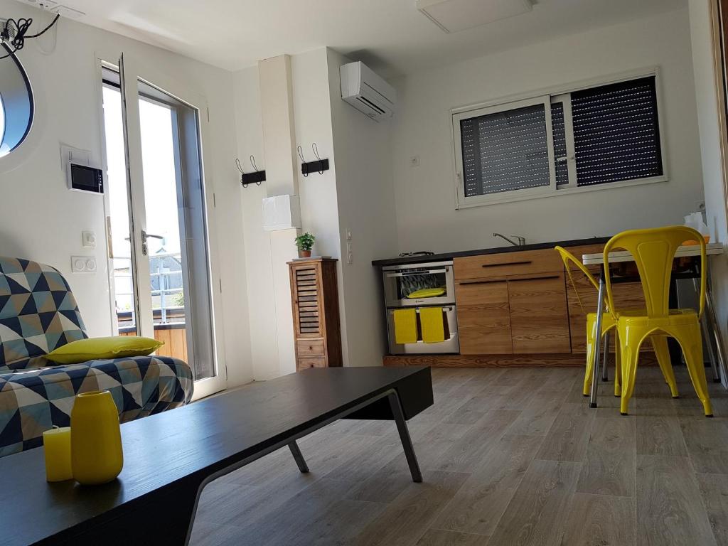 ein Wohnzimmer mit einem Tisch und gelben Stühlen in der Unterkunft Angers Green Lodge - Yellow Sun Appartement in Angers