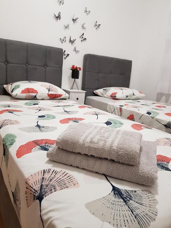 2 Betten in einem Zimmer mit Schmetterlingen an der Wand in der Unterkunft Kabashi Apartment in Krk
