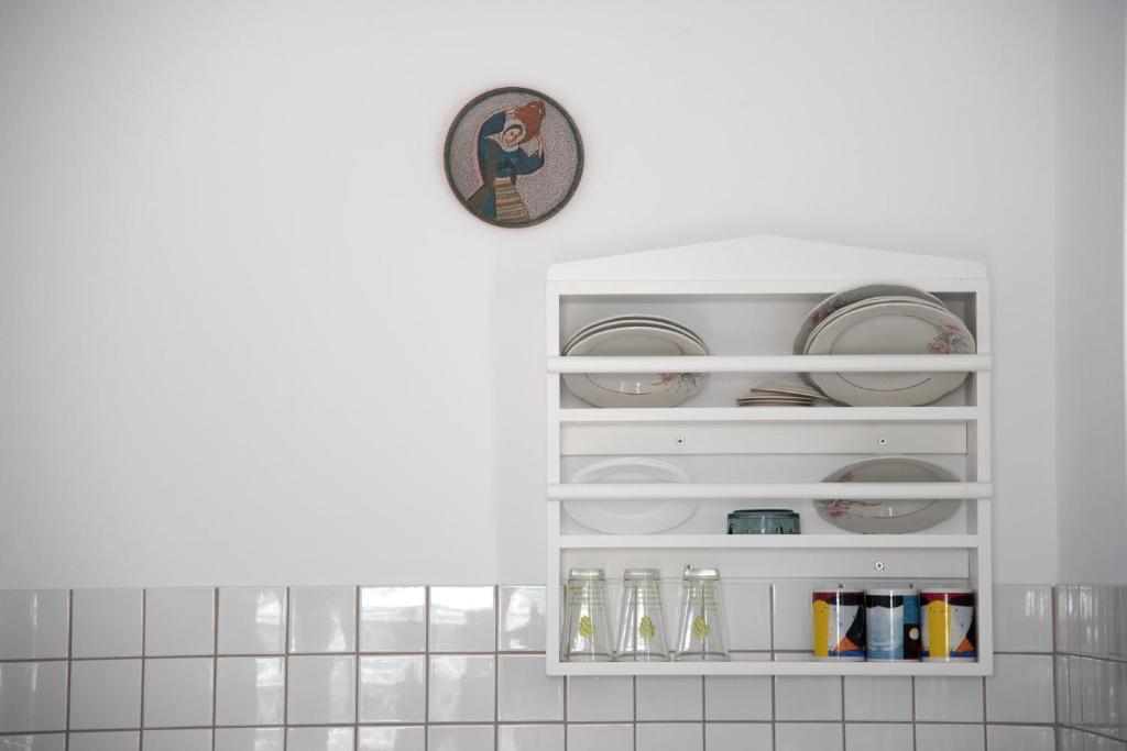a white cabinet with plates and glasses in it at Paroscarmel studio-apartment in Logaras