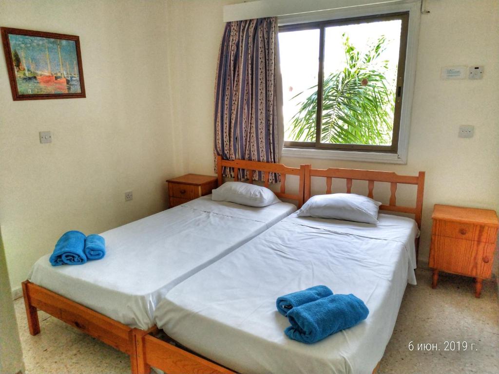 Dos camas en un dormitorio con toallas azules. en Constantaras Apartments, en Protaras