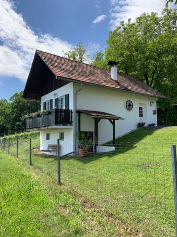 a white house with a porch and a balcony at Weinbergstöckl Gombotz in Neuhaus am Klausenbach