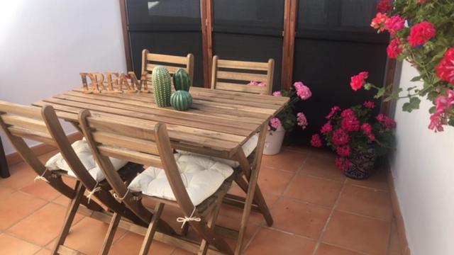 einen Holztisch und Stühle mit Blumen auf der Terrasse in der Unterkunft ATICO SAN MARCOS in El Puerto de Santa María