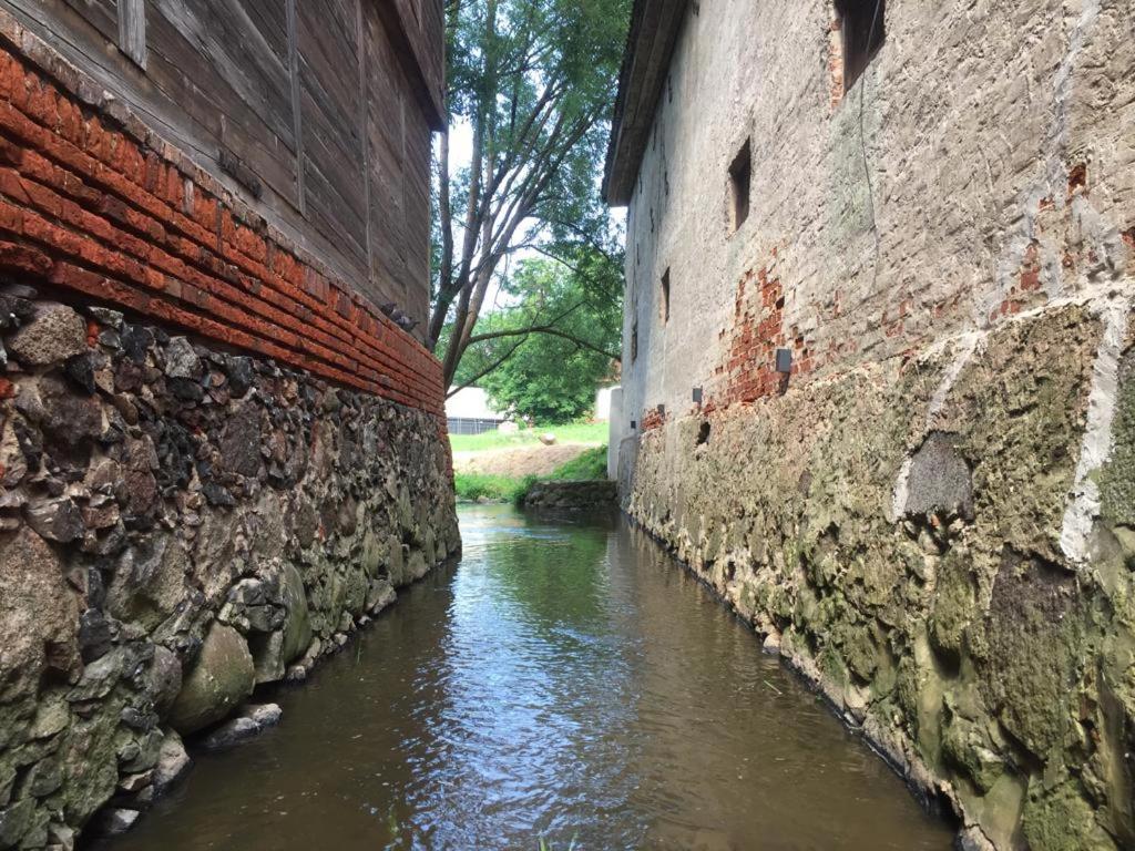 an alley between two brick buildings next to a river at Maza Venecija-Kuldiga in Kuldīga