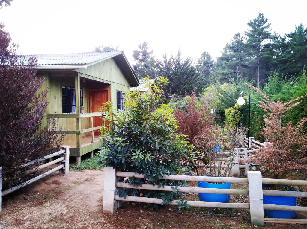une maison avec une clôture en face d'un jardin dans l'établissement Cabañas El Colibrí, à Algarrobo