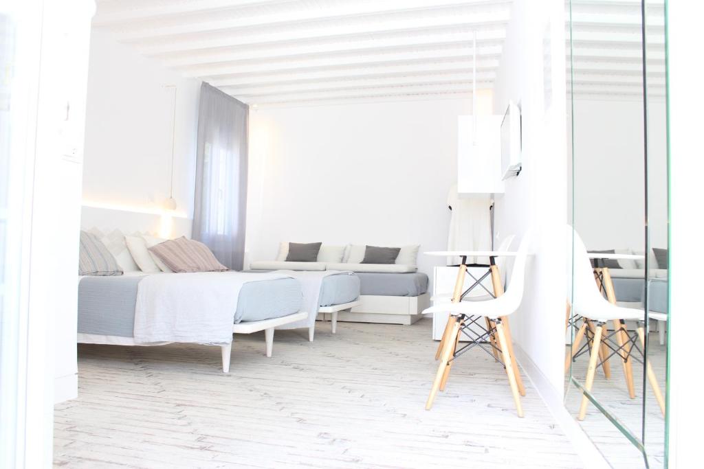 a white bedroom with a bed and a desk at Christina Studios in Mikonos