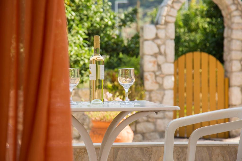 stół z 2 kieliszkami i butelką wina w obiekcie Ancient Assini Apartments w mieście Tolo