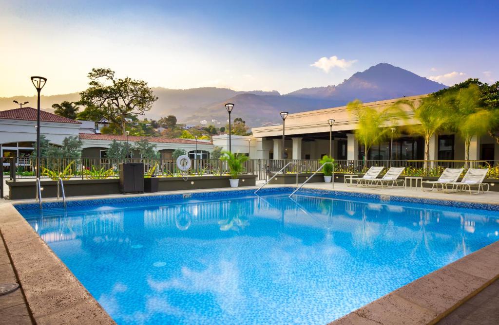 a large blue swimming pool in front of a building at Plaza Hotel and Suites in San Salvador