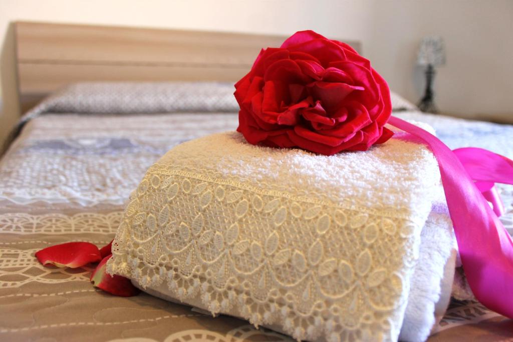 una rosa rossa seduta sopra un letto di Confortevole Appartamento a pochi passi dal Centro ad Alghero