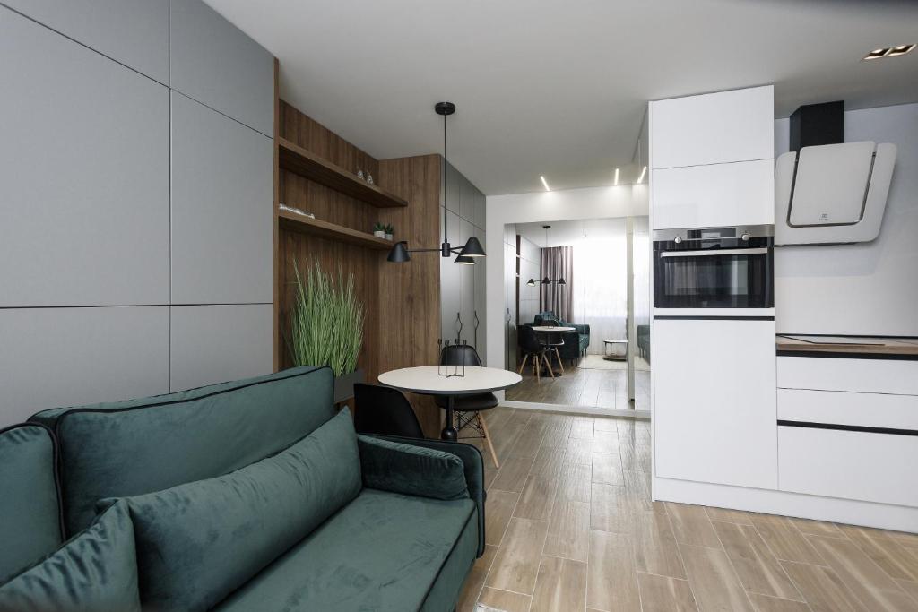 a living room with a green couch and a kitchen at City Center Apartment in Siauliai in Šiauliai