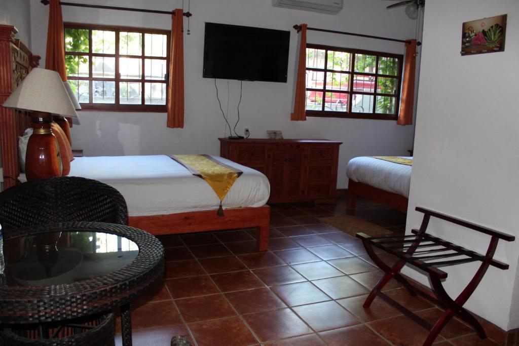 a bedroom with a bed and a chair and a tv at Villas Amalia Hotel in Sayulita