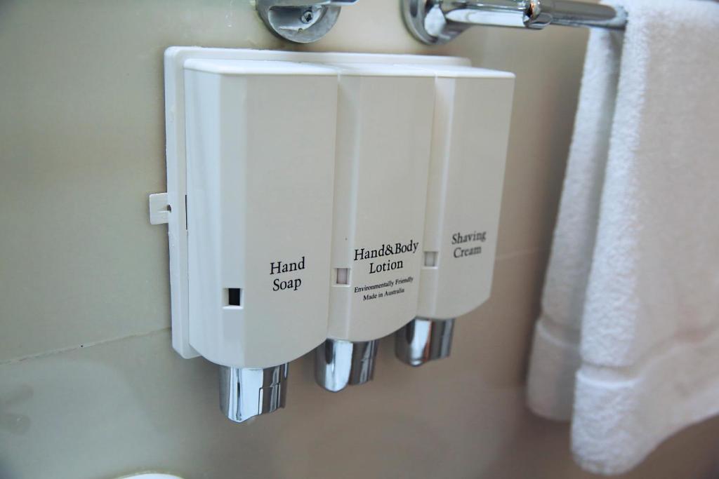 a bathroom with two soap dispensers on a wall at Metro Inn Ryde in Sydney