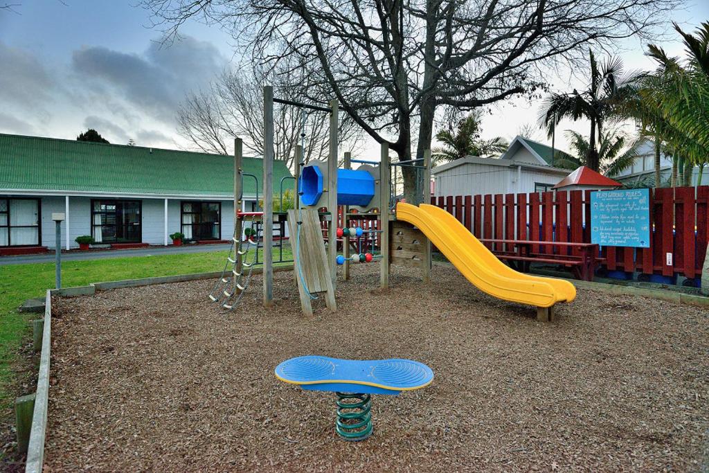 a playground with a yellow and blue slide and a swing at Auckland Northshore Motels & Holiday Park in Auckland