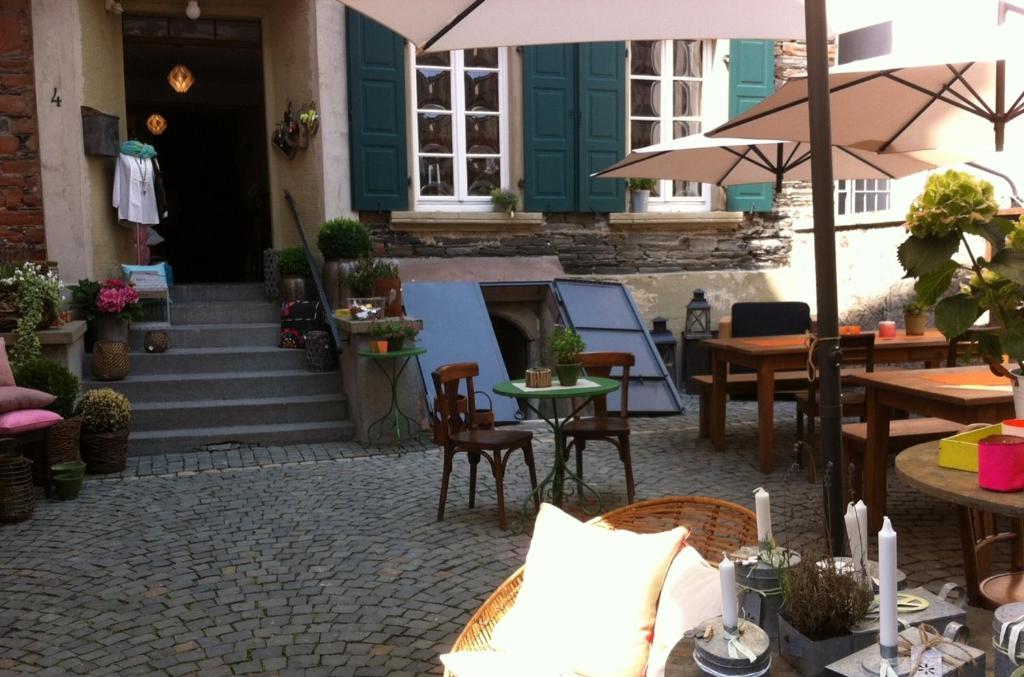un patio al aire libre con mesas, sillas y una sombrilla en Melcher`s, en Bernkastel-Kues