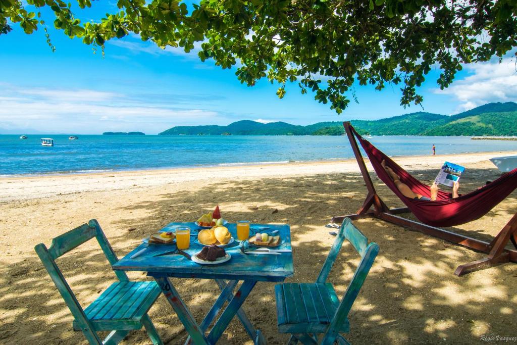 uma mesa com um prato de comida e duas cadeiras numa praia em Geko Pousada Paraty em Paraty