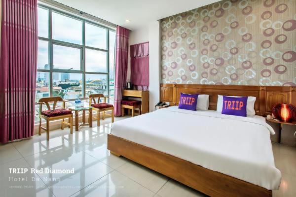 Un dormitorio con una cama grande y una mesa con sillas. en Red Diamond Hotel, en Da Nang