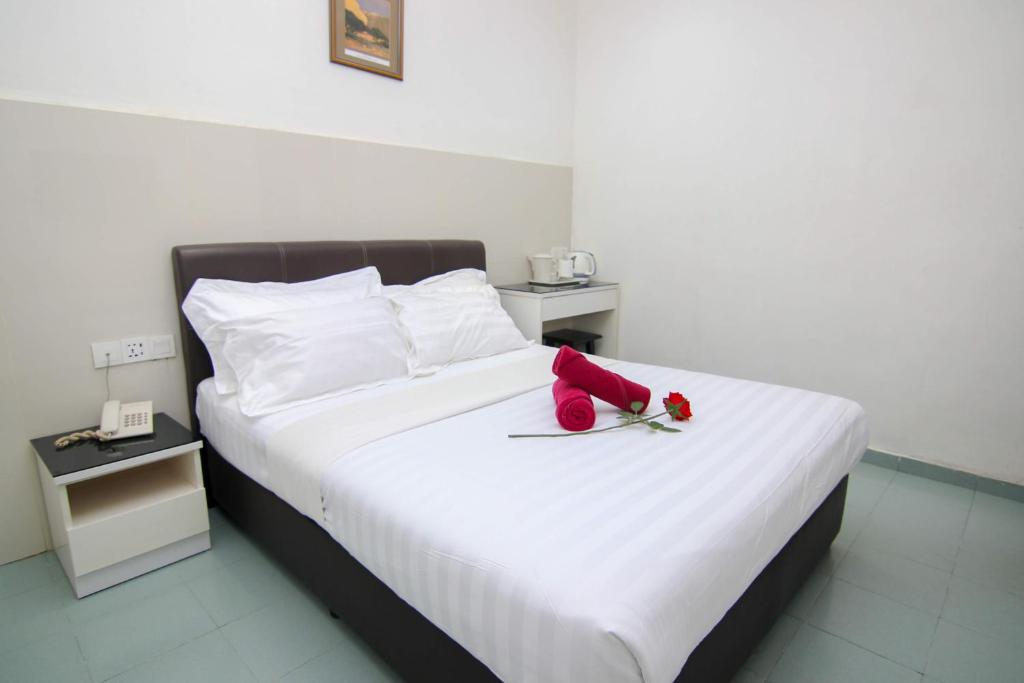 a white bed with red roses on top of it at Rose Cottage Hotel Taman Johor Jaya in Johor Bahru