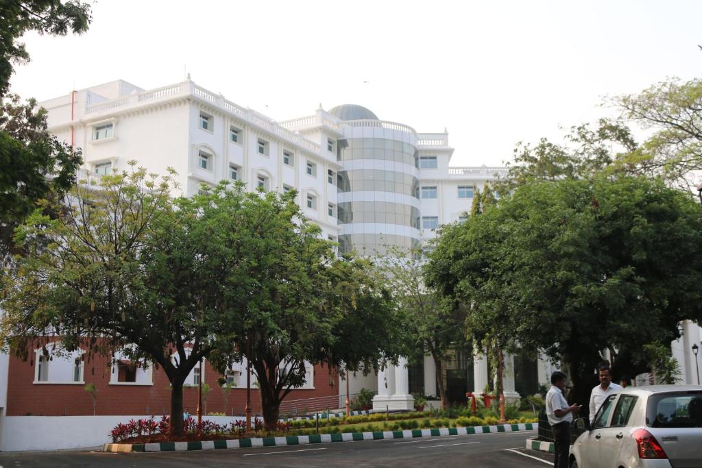 een wit gebouw met bomen ervoor bij KSTDC KumaraKrupa Hotel in Bangalore