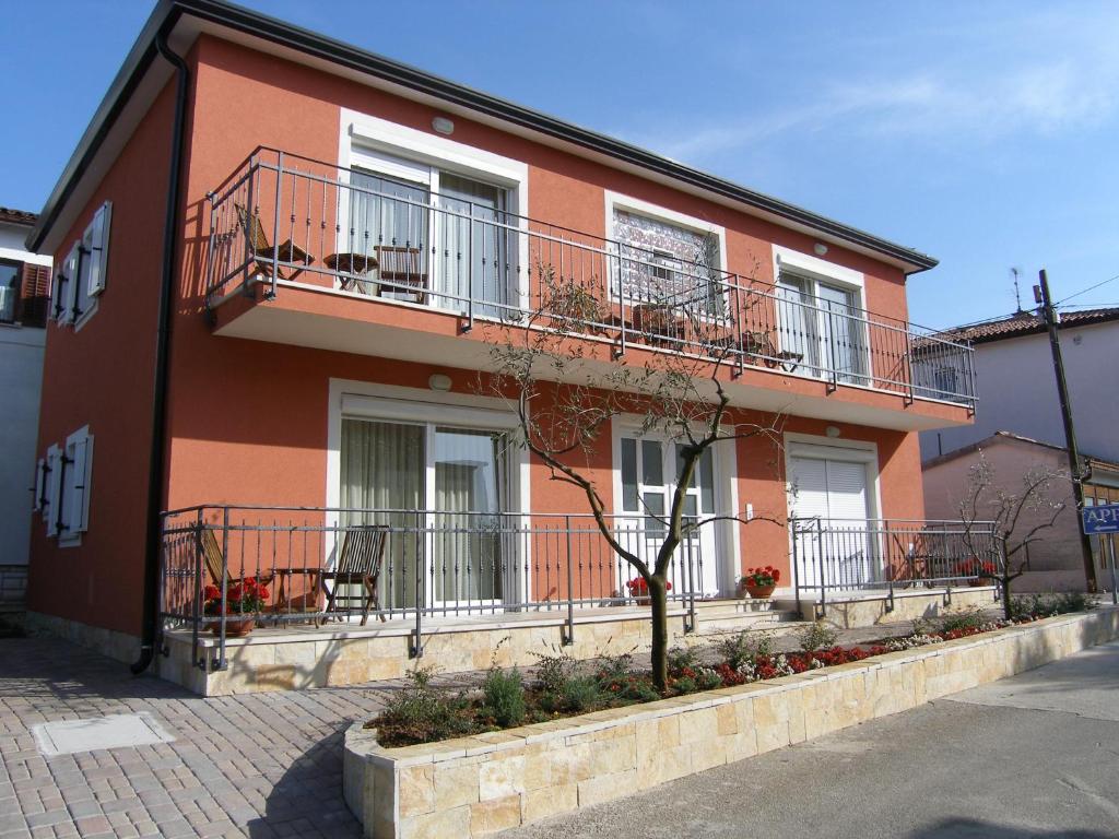 un edificio rojo con balcones, mesas y sillas en Apartments Nina, en Umag