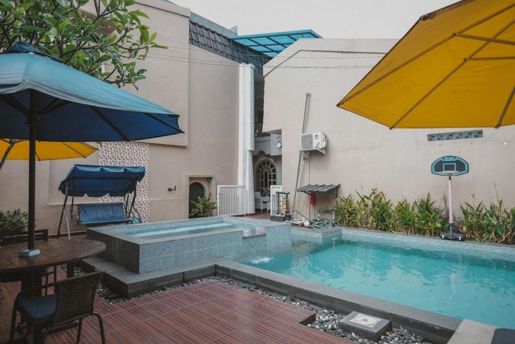 a swimming pool next to a building with an umbrella at RedDoorz Plus @ Tanjung Karang Lampung 2 in Bandar Lampung