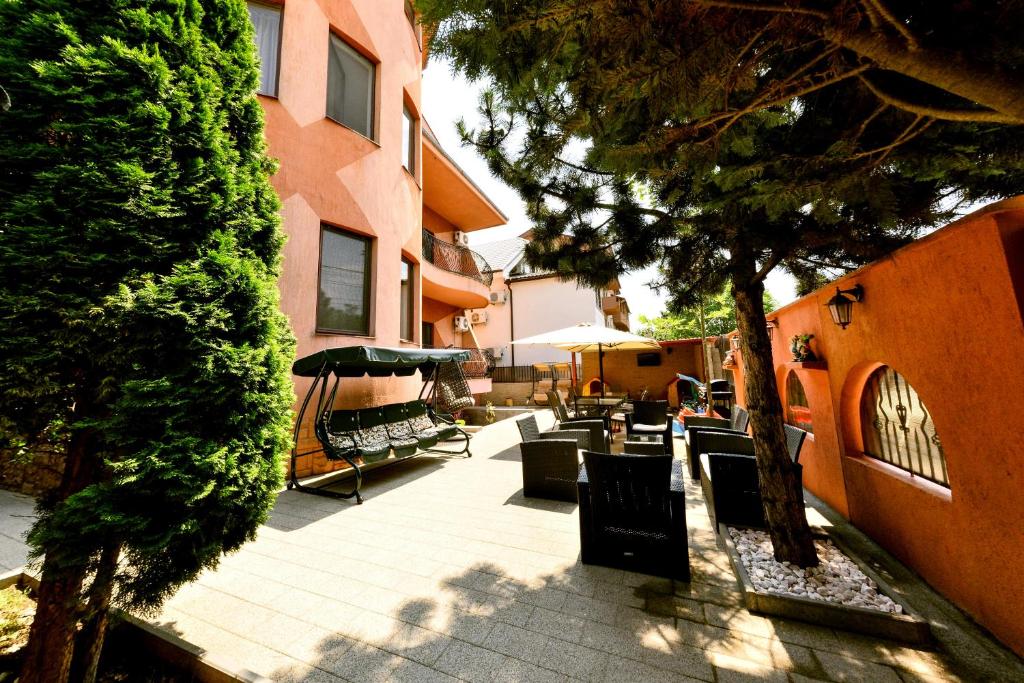 an outdoor patio with chairs and trees and a building at Vila Eden in Eforie Nord