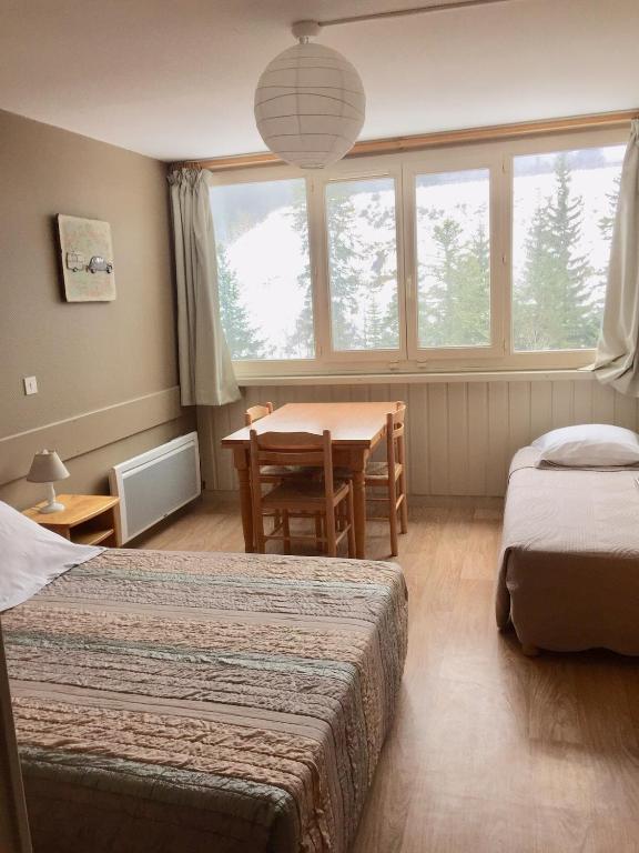 une chambre avec deux lits, une table et une fenêtre dans l'établissement RÉSID BEC DE L AIGLE Studio 21 - LE LIORAN, à Laveissière