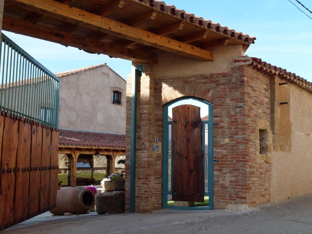 een bakstenen gebouw met een houten deur en een hek bij Hotel Rural El Perdigón in El Perdigón