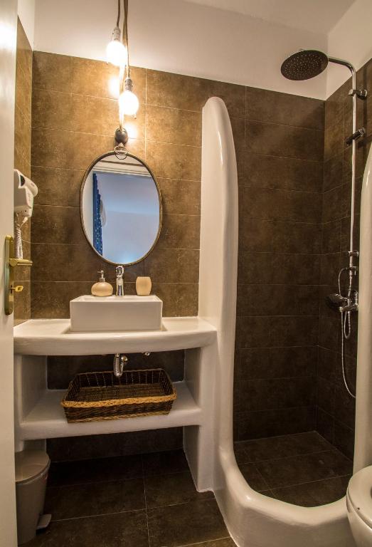 a bathroom with a sink and a tub and a mirror at Pension Ioanna in Adamantas