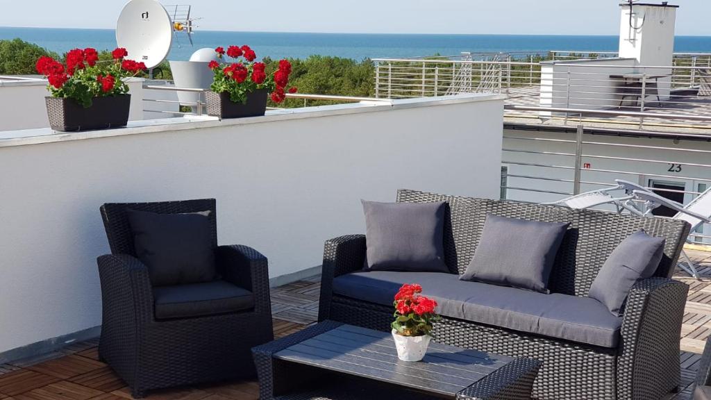 - une terrasse avec 2 chaises, une table et des fleurs dans l'établissement Apartament z tarasem na dachu B22, à Rowy