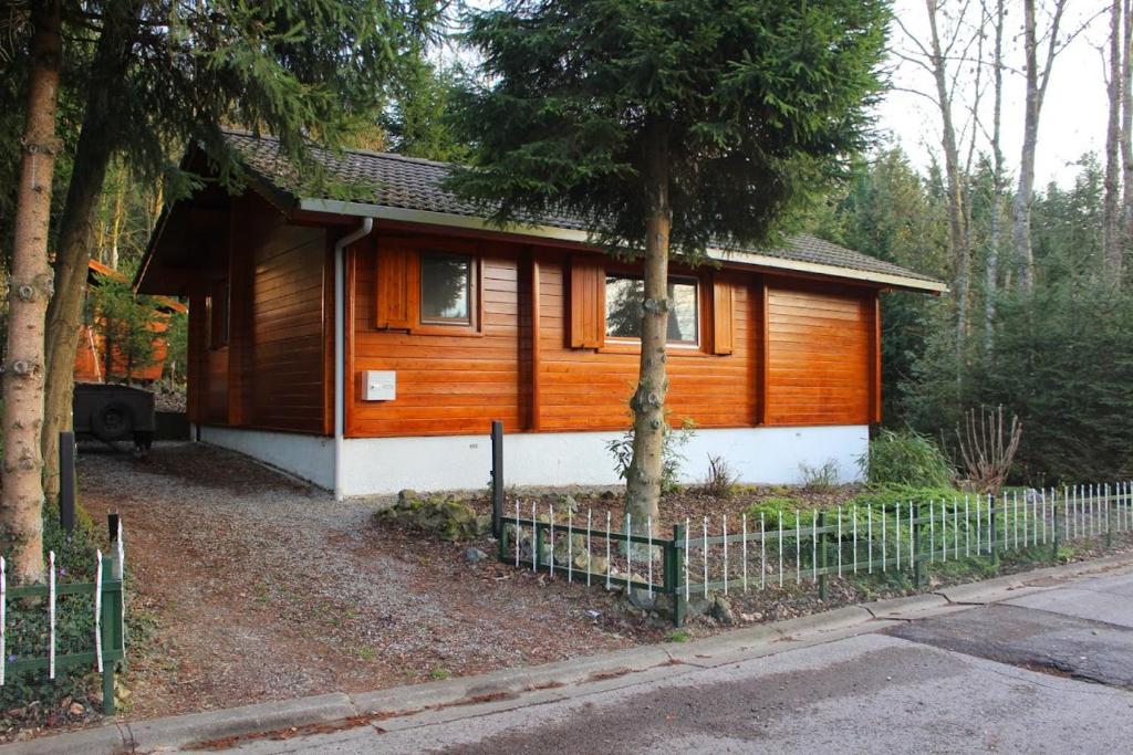 uma pequena casa de madeira com uma cerca em frente em Chalet Dennerust - The Original em Durbuy