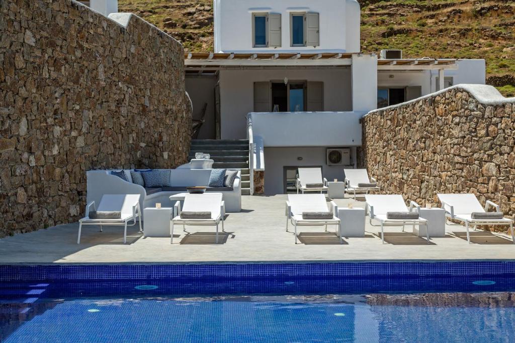 a group of white lounge chairs and a swimming pool at Mykonos Panormos Villas in Mykonos