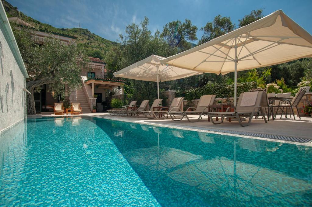 a swimming pool with chairs and umbrellas next to at Villa Stevan in Sveti Stefan