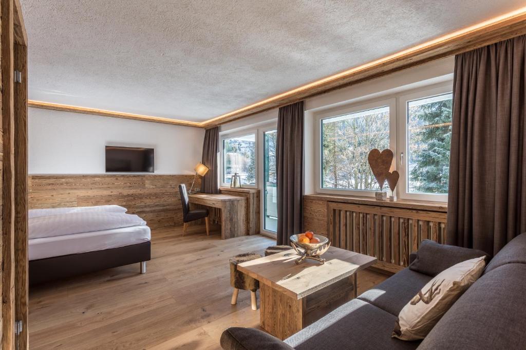 a hotel room with a bed and a couch at Almhof Kitzlodge - Alpine Lifestyle Hotel in Kirchberg in Tirol