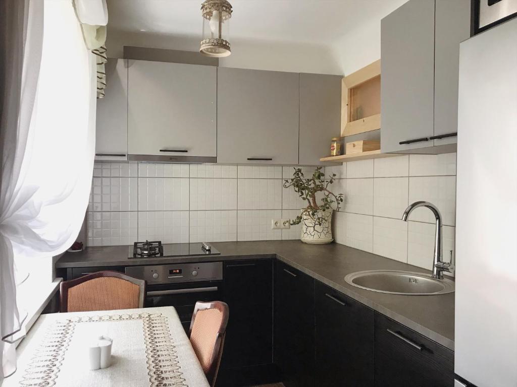a kitchen with white cabinets and a sink and a table at P. Stradiņa iela 17 Апартаменты in Ventspils