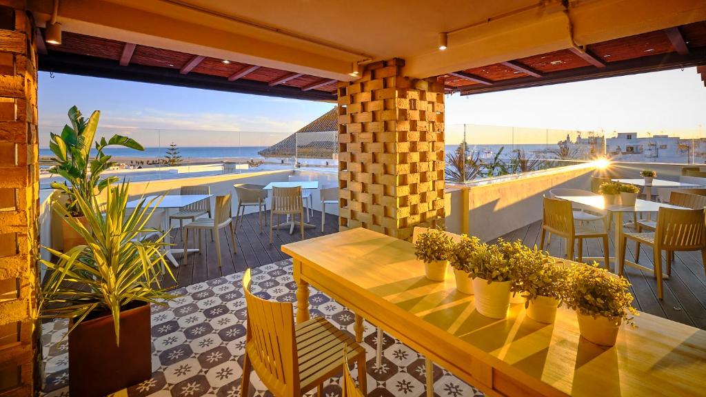 a patio with tables and chairs and a view of the ocean at Hostal Campito in Conil de la Frontera