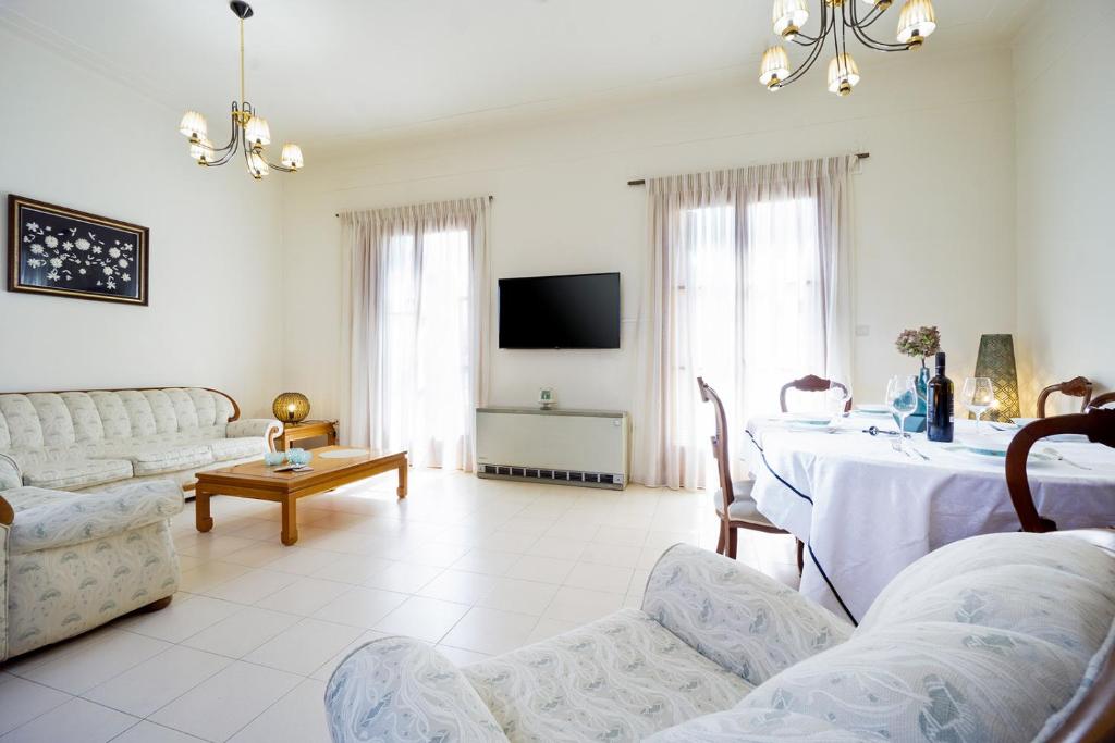 Una sala de estar con una mesa y un televisor. en Metropolis House, en La Canea