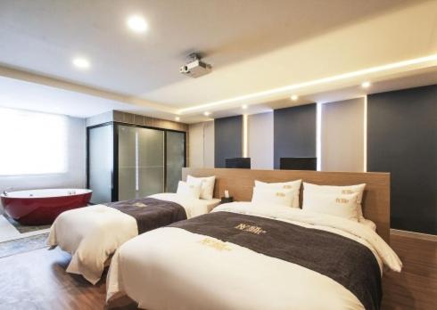1 dormitorio con 2 camas y bañera. en No.1 New Yorker Hotel en Jinju