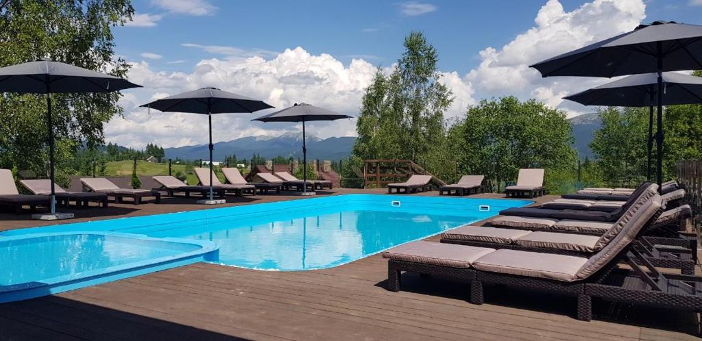 a swimming pool with lounge chairs and umbrellas at GOOD DAYS Shale Resort 4 км до Буковеля in Yablunytsya