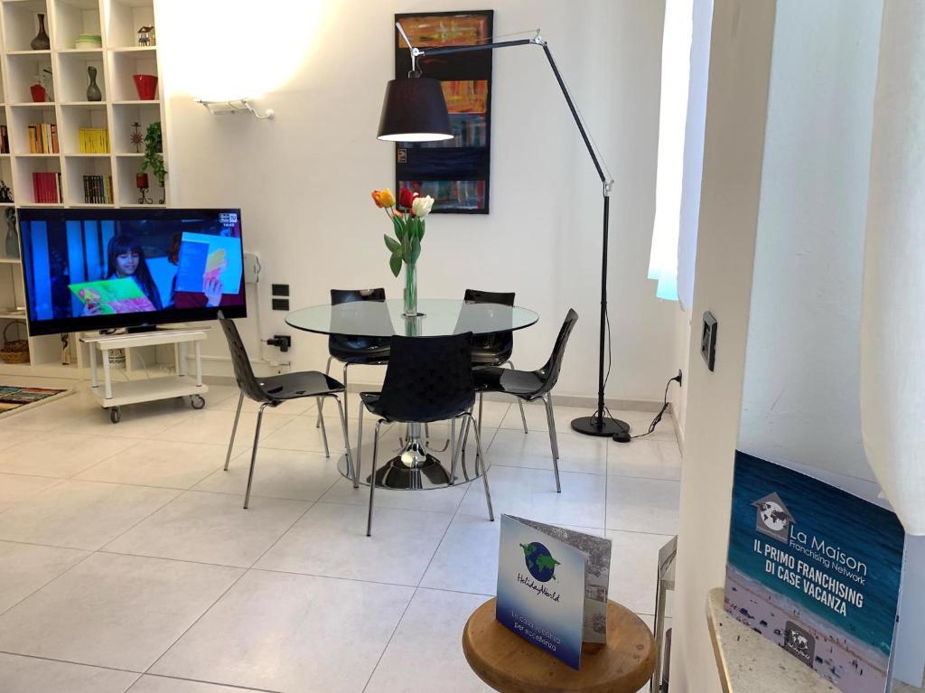 - une salle à manger avec une table, des chaises et une télévision dans l'établissement House Sarzano by Holiday World, à Gênes