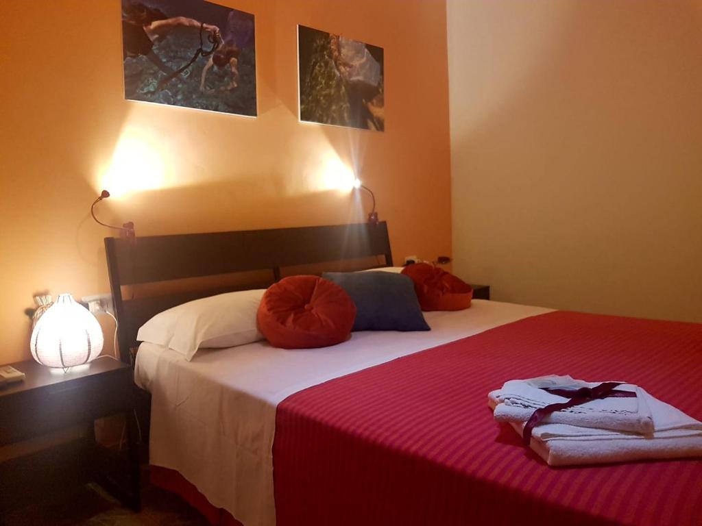 a bedroom with a bed with red sheets and pillows at Driade B&B in Milazzo
