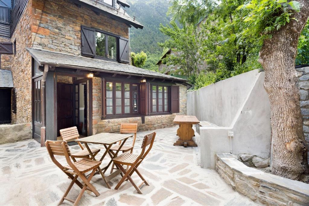 a patio with a table and chairs in front of a house at Luderna - Casa con terraza dera Aubeta in Garós