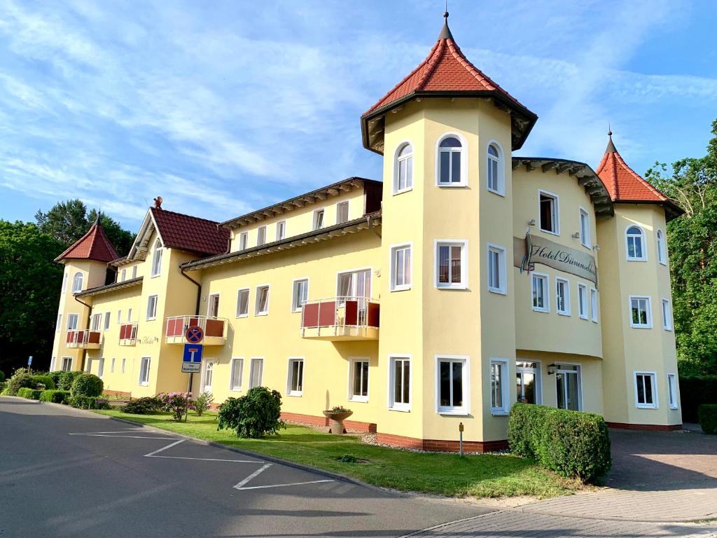 un gran edificio amarillo con techo rojo en Hotel Dünenschloss, en Ostseebad Karlshagen