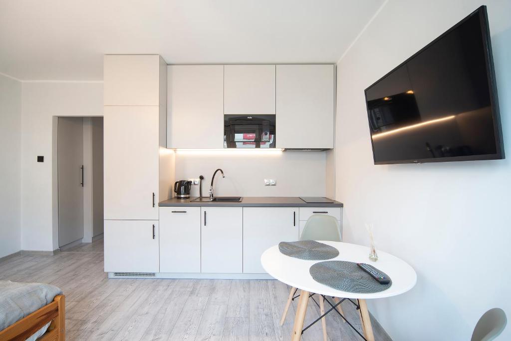 uma cozinha com armários brancos, uma mesa e um lavatório em IV apart em Gdynia