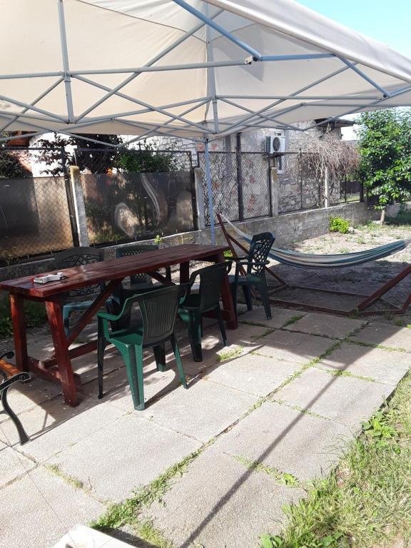 a picnic table and chairs under an umbrella with a hammock at Old House in Vama Veche