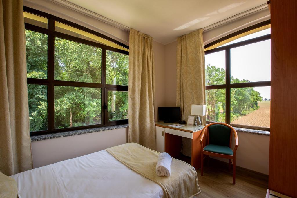a bedroom with a bed and a desk and windows at La Bergamina Hotel & Restaurant in Arcore