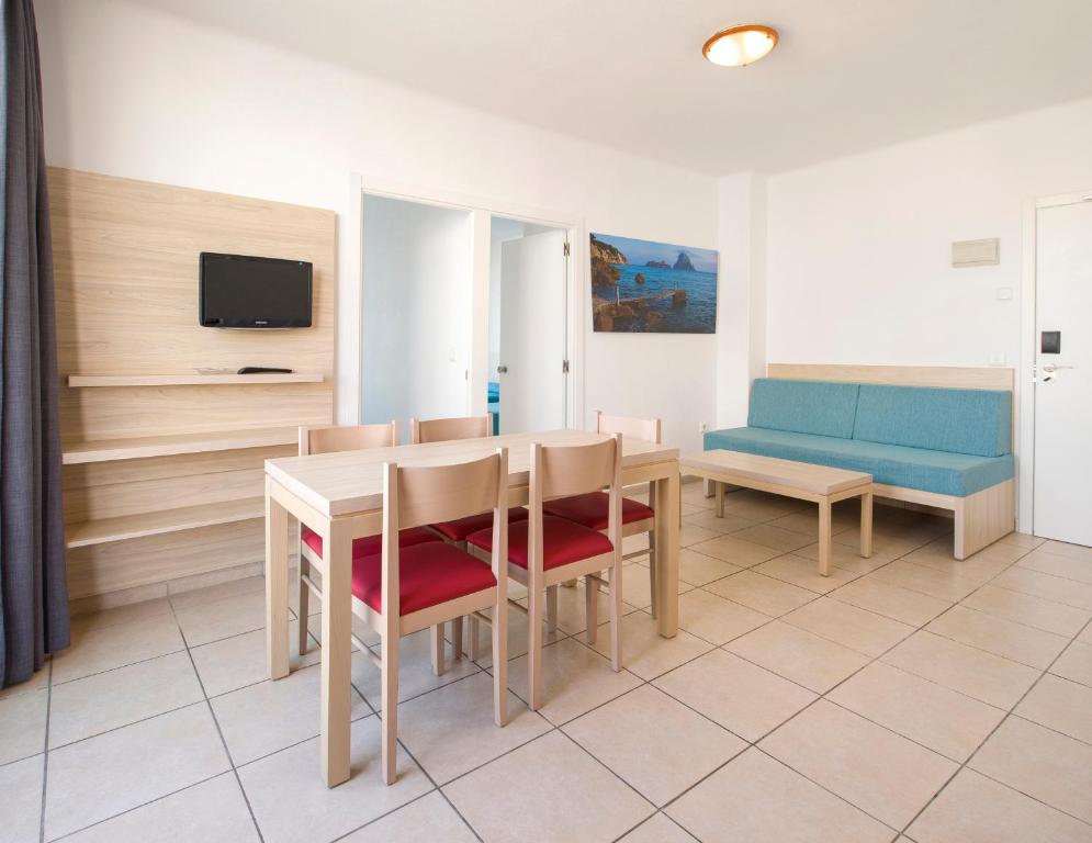 a dining room with a table and chairs and a couch at Apartamentos Tramuntana in San Antonio