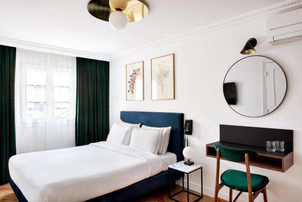 een slaapkamer met een bed, een tafel en een spiegel bij Hotel Rendez-Vous Batignolles in Parijs