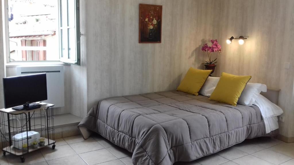 a bedroom with a bed with yellow pillows and a television at Le Petit St Jacques in Le Puy en Velay