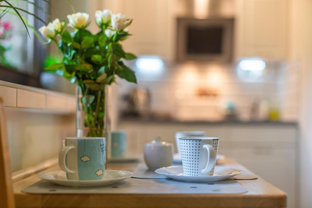 a table with two cups and a vase with flowers at Apartament Ewa in Zakopane