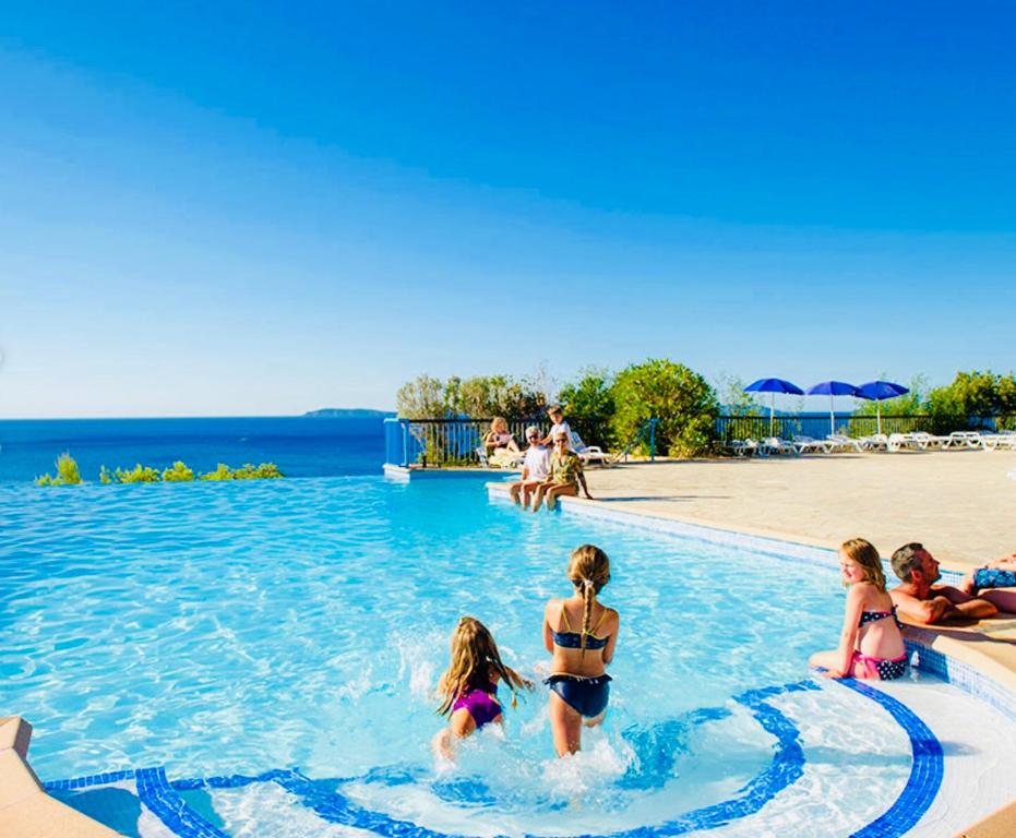 een groep kinderen in een zwembad in een resort bij Mazet « Domaine de la pinède » in Le Lavandou